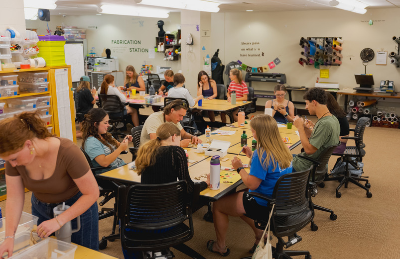 Students sit around at table working on a project